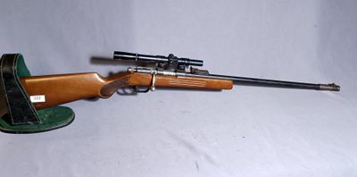 the rifle is sitting on the table next to the hat