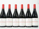 six bouteilles de vin rouge sont alignées sur une table