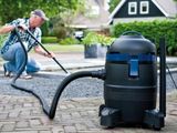 un homme en train de nettoyer une allée à l'aide d'un aspirateur