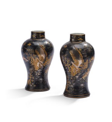 une paire de vases noirs et dorés posés sur une surface blanche
