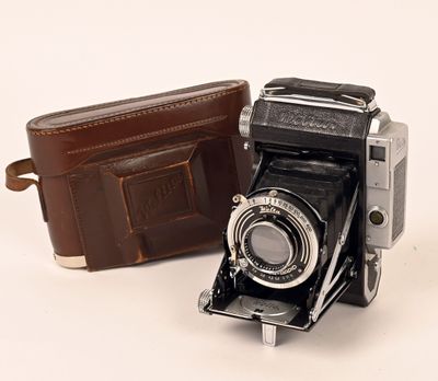 un portefeuille en cuir marron à côté d'un vieil appareil photo