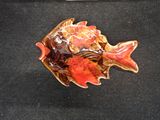 a ceramic fish that is sitting on a black surface