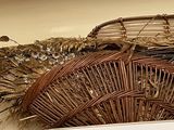 a wicker basket on top of a refrigerator next to a basket of dried plants
