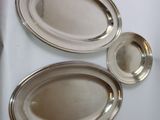 trois plateaux ovales en argent posés sur un plateau de table blanc