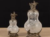 two glass vases sitting on top of a table next to each other