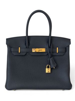 un sac à main en cuir noir muni d'un cadenas sur la poignée