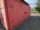 a red container sitting in the middle of a parking lot
