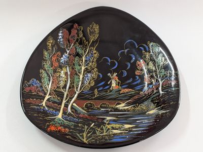 an image of a black plate with a painting of a river and trees
