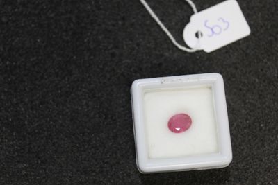 a pink stone in a square container next to a tag