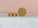two gold coins sitting next to each other on a marble surface