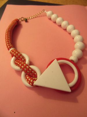 a red and white necklace with a white triangle on it