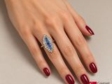 an image of a woman ' s hand with red nails and a blue and white diamond ring