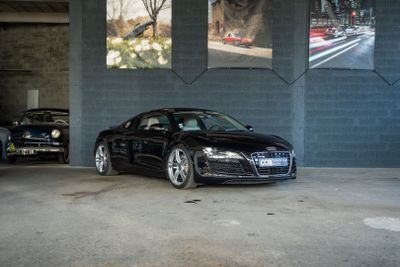 une Audi noire garée dans un parking à côté de deux vieilles voitures