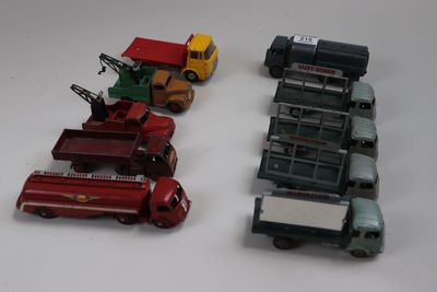 Plusieurs camions miniatures sont alignés sur une surface blanche