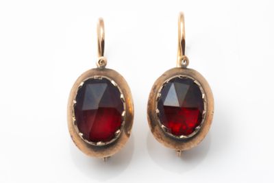 une paire de boucles d'oreilles ornées de grenats rouges sur fond blanc