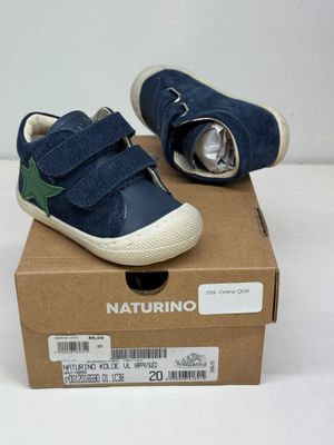 des chaussures de petit garçon dans une boîte posée sur une surface blanche