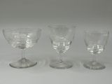 three clear wine glasses sitting on top of a white table