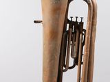 an old brass musical instrument sitting on top of a white surface