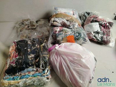 many bags of clothing on the floor next to a pair of scissors