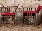 four red chairs sitting in a row in a field