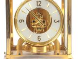 a gold clock with a white face on a white background