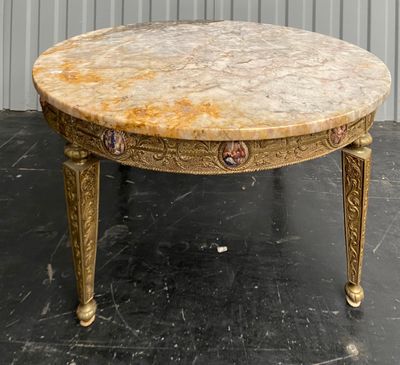 a marble top table with gold legs on a black floor