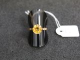 une bague ornée d'une pierre jaune, posée sur une table