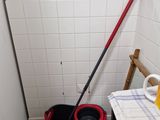 a mop and a bucket on the floor in a bathroom