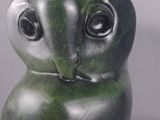 sculpture of a green owl sitting on top of a white surface