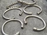 plusieurs bracelets en argent et une chaîne posés sur une table