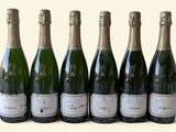 six bouteilles de champagne alignées sur une surface blanche
