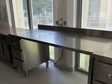 une grande table de travail en acier inoxydable au milieu d'une pièce