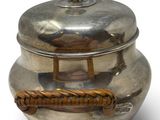 a silver pot with a rope handle on a white surface