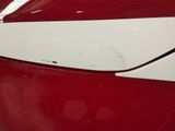 the rear end of a red car with a white stripe