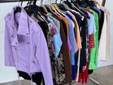 beaucoup de vêtements suspendus à une étagère dans une pièce