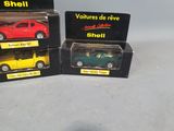 three toy cars are in boxes on a white surface