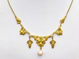 a gold necklace with pearls on a mannequin neck