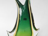 a green and yellow glass vase sitting on a white surface