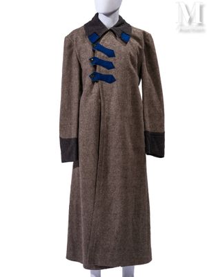 Ce manteau est en laine et comporte un ruban bleu au niveau du col.