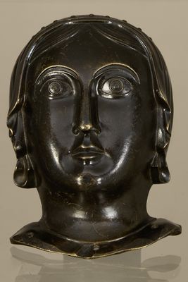 bronze head of a woman with ear rings on a white surface