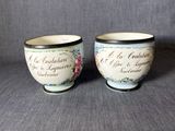 deux petites tasses portant une inscription, posées sur une surface grise