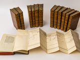 several old books sitting on top of each other on a white surface