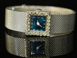 an image of a silver bracelet with a blue square watch on it