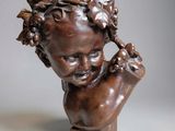 un buste antique en bronze représentant un enfant avec des grappes de raisin sur la tête