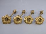 quatre bougeoirs dorés en forme de fleur posés sur une surface blanche