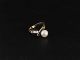 une bague en or sertie d'une perle et de diamants sur un fond noir