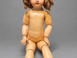 an old wooden doll sitting on a gray surface with a gray background