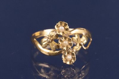 un gros plan d'une bague en or ornée de fleurs