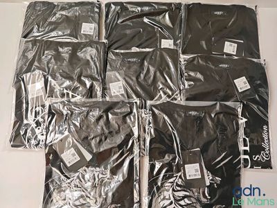 six sacs de t-shirts noirs posés sur une table