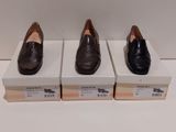 trois paires de chaussures sont posées sur des cartons, sur une surface blanche